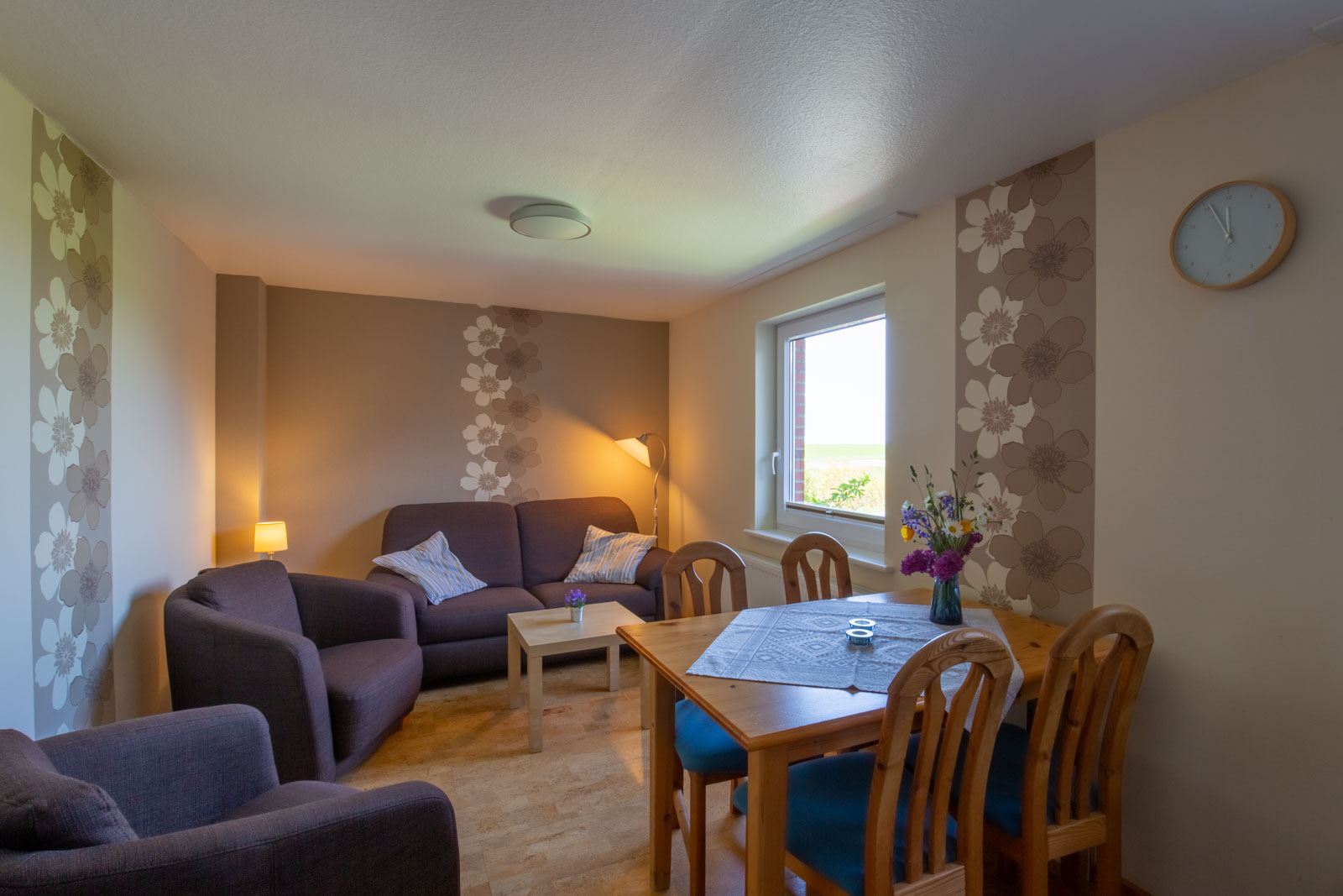 Wohn- und Essbereich der Ferienwohnung Amrum für den Urlaub an der Nordsee auf der Nordseeinsel Pellworm mit Sofa, Sessel und Esstisch