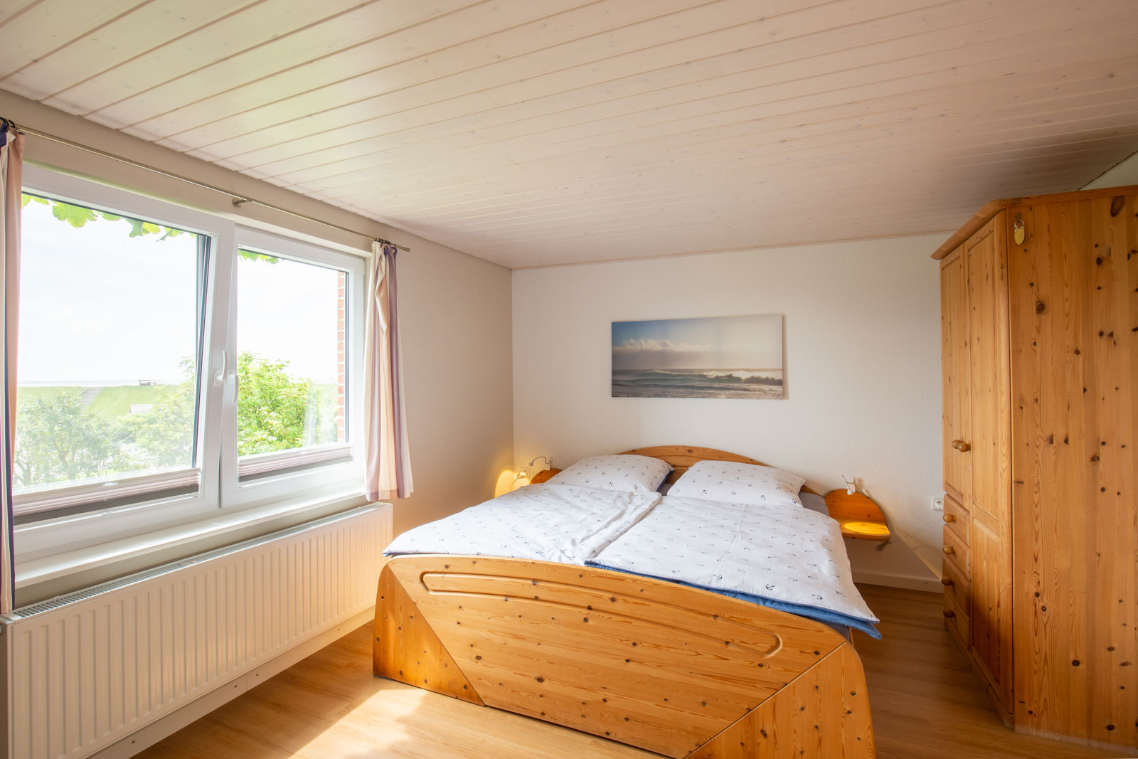 Helles Schlafzimmer der Ferienwohnung Norderoog für den Urlaub an der Nordsee auf der Nordseeinsel Pellworm mit Doppelbett und Ausblick